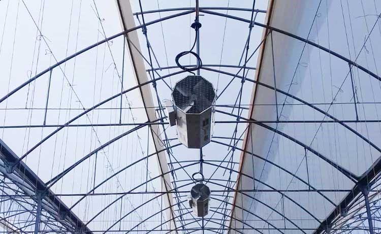The Bloom Greenhouse Heater with Vent Mode hanging in a greenhouse.